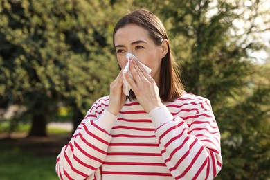 Photo of Woman with napkin suffering from seasonal allergy outdoors