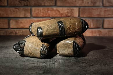 Photo of Hemp in packages on grey table near brick wall. Drug addiction