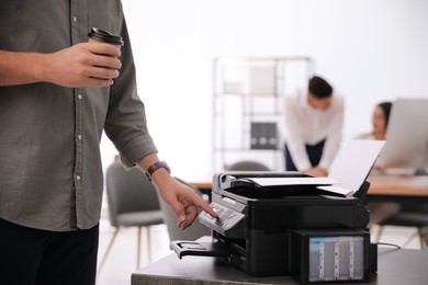 Photo of Employee using modern printer in office, closeup