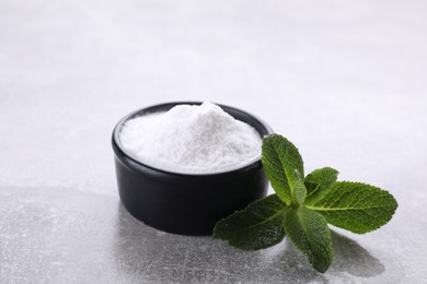 Photo of Sweet fructose powder and mint leaves on light grey table