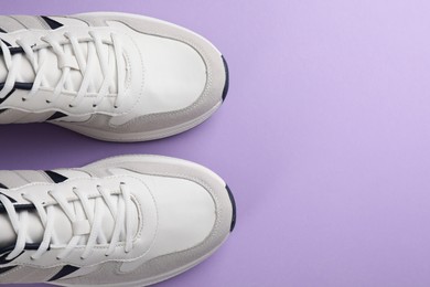 Photo of Pair of stylish sports shoes on lilac background, flat lay. Space for text