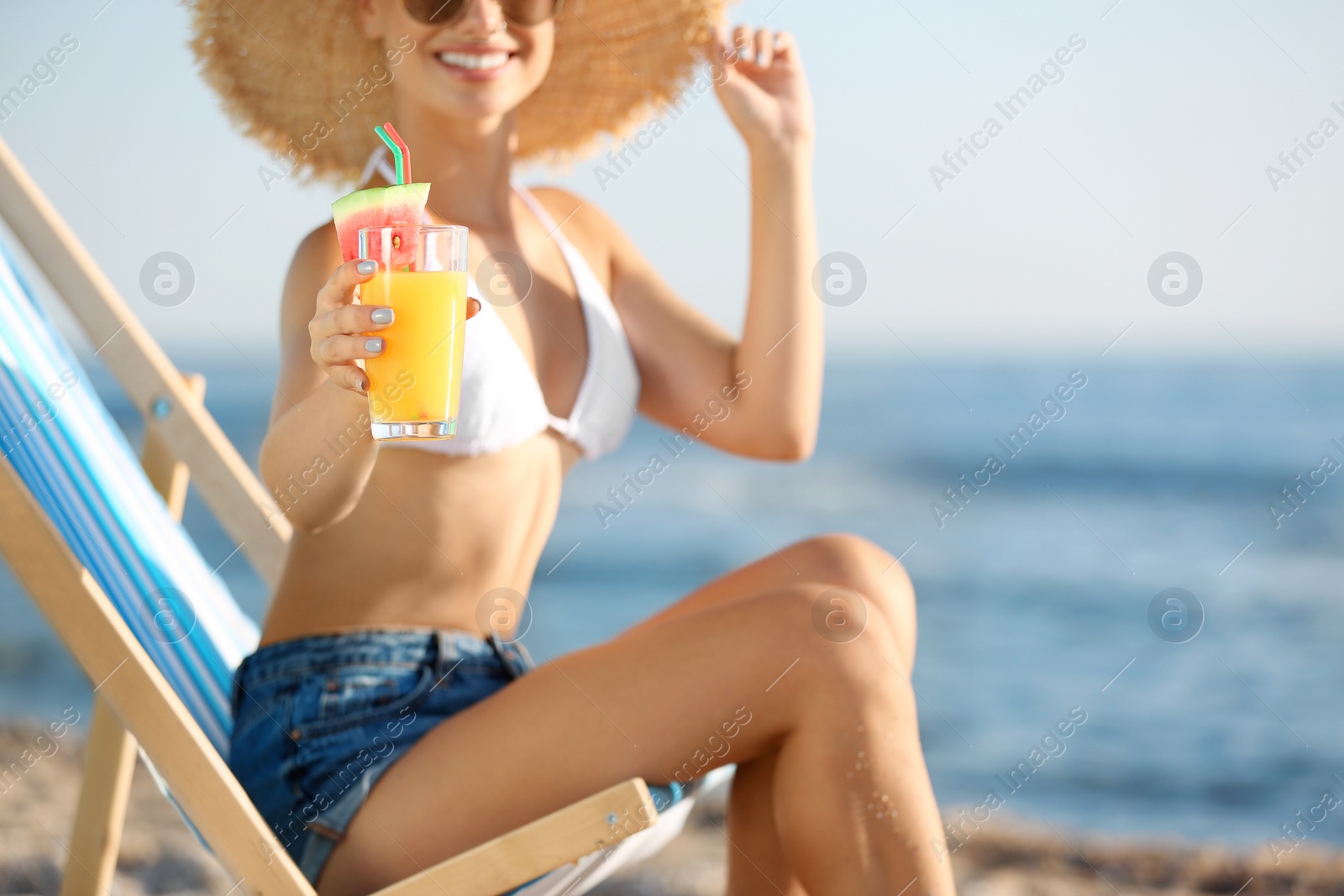 Photo of Young woman with cocktail in beach chair at seacoast