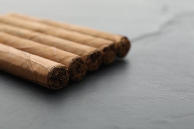 Photo of Many cigars on grey table, closeup. Space for text