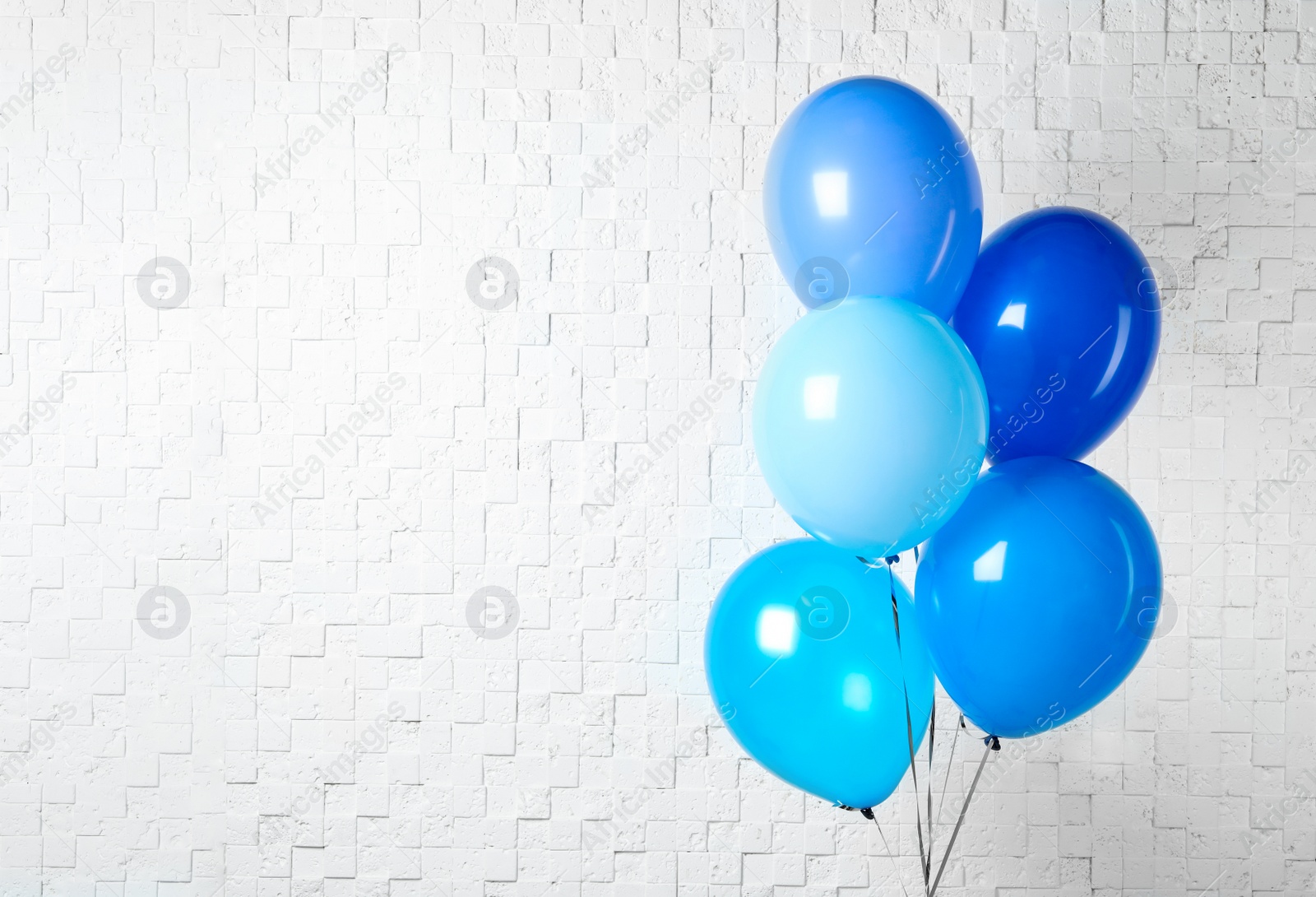 Photo of Bunch of blue balloons near white wall, space for text. Greeting card