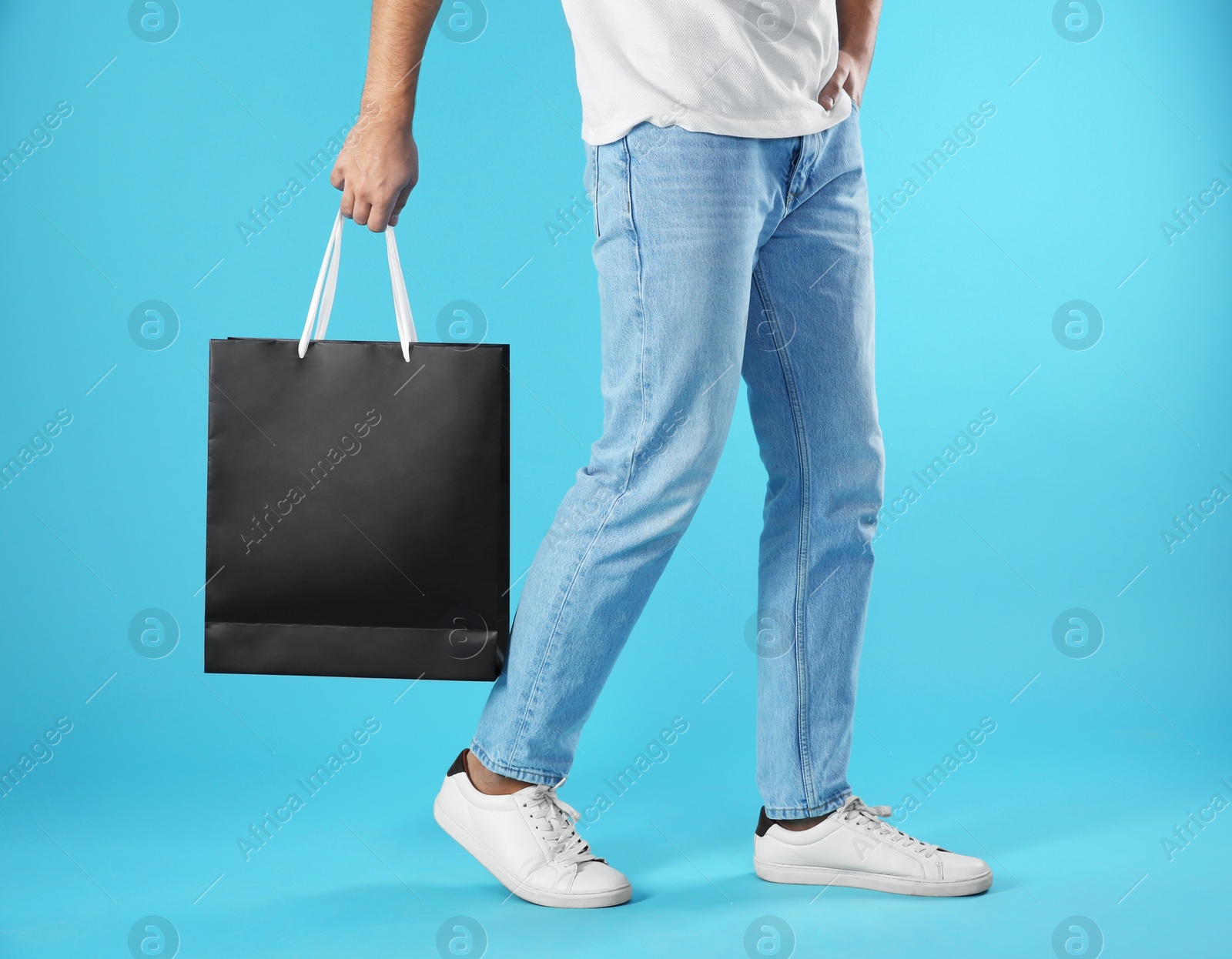 Photo of Young man holding paper bag on color background, closeup.  Mockup for design