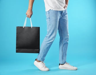 Young man holding paper bag on color background, closeup.  Mockup for design