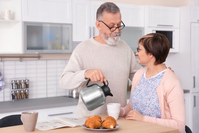 Photo of Happy senior couple having breakfast together at home