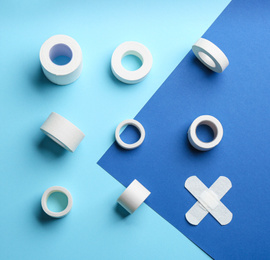 Different types of sticking plasters on blue background, flat lay