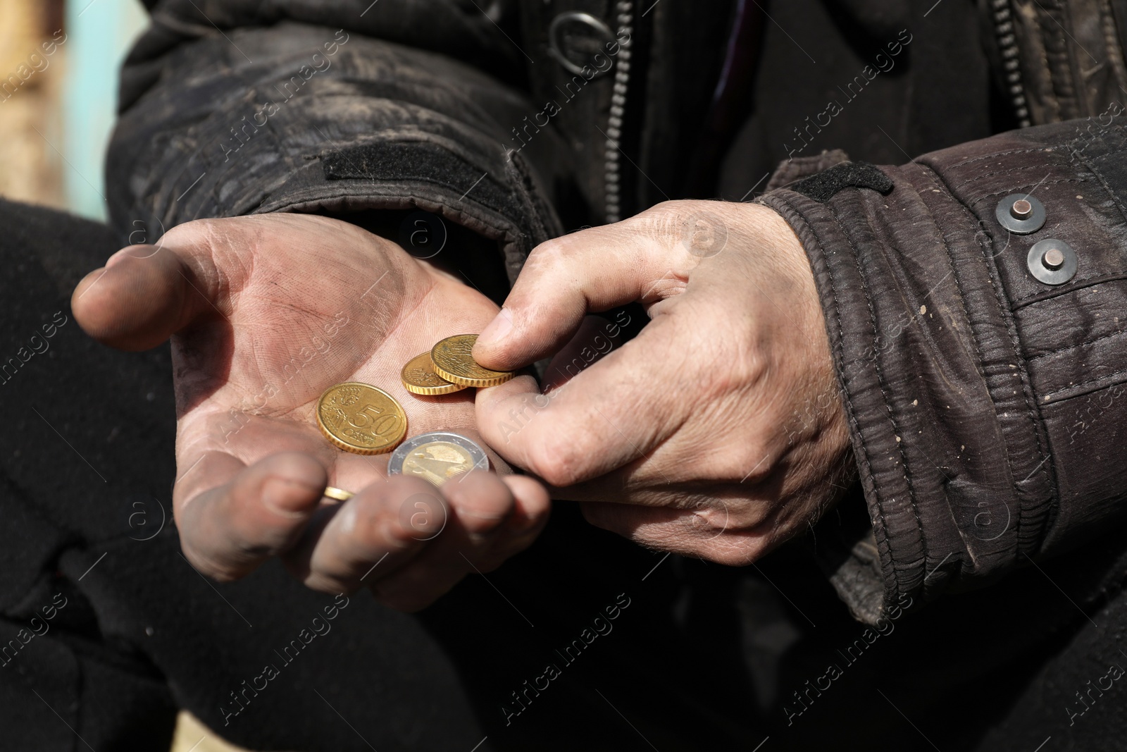 Photo of Poor homeless man holding coins outdoors, closeup