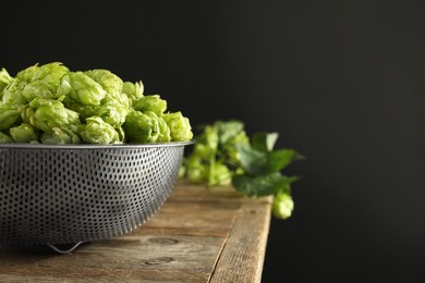 Fresh green hops on wooden table against black background, space for text