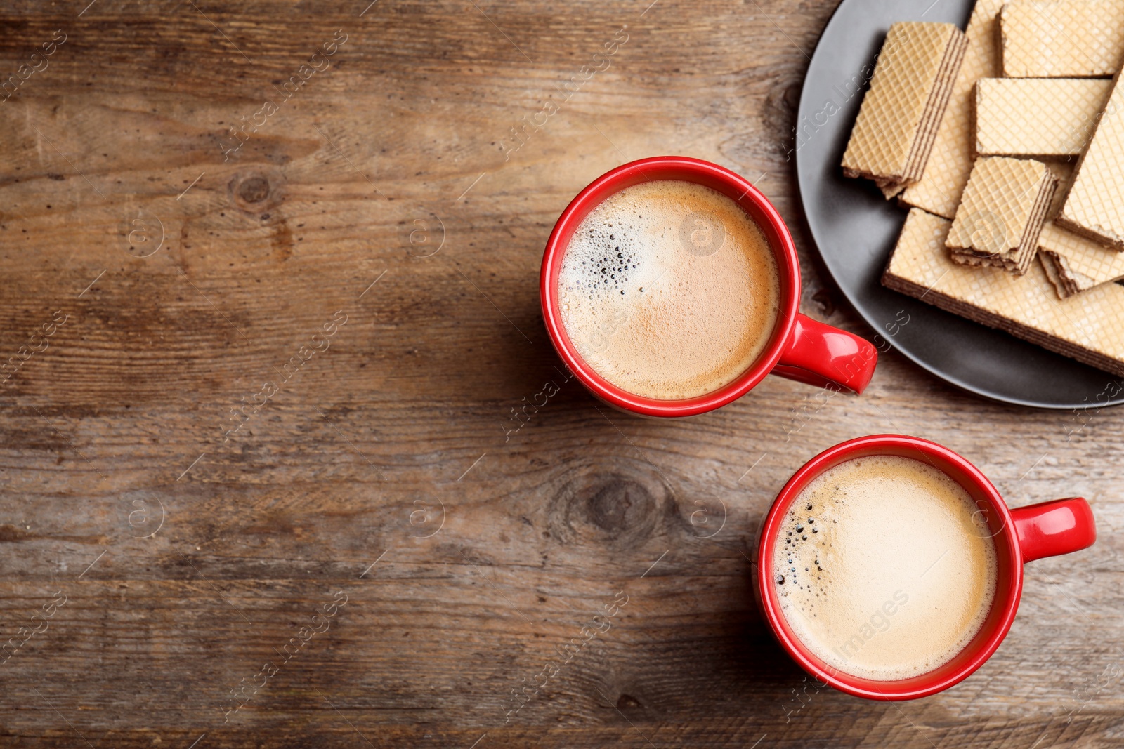 Photo of Breakfast with delicious wafers and coffee on wooden table, flat lay. Space for text