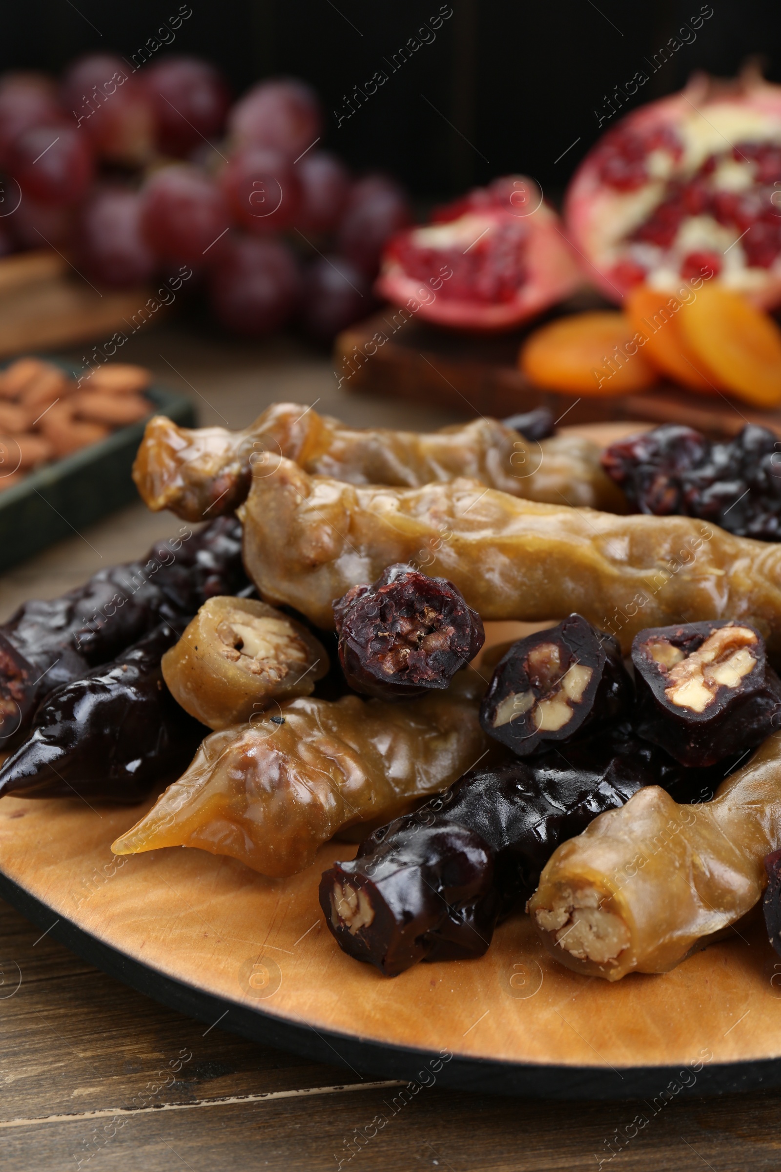 Photo of Many delicious sweet churchkhelas on wooden table, closeup