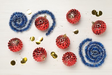 Blue tinsel, confetti and Christmas balls on white wooden background, flat lay