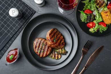Photo of Delicious beef medallions served on grey table, flat lay