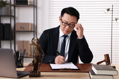 Notary writing notes at wooden table in office