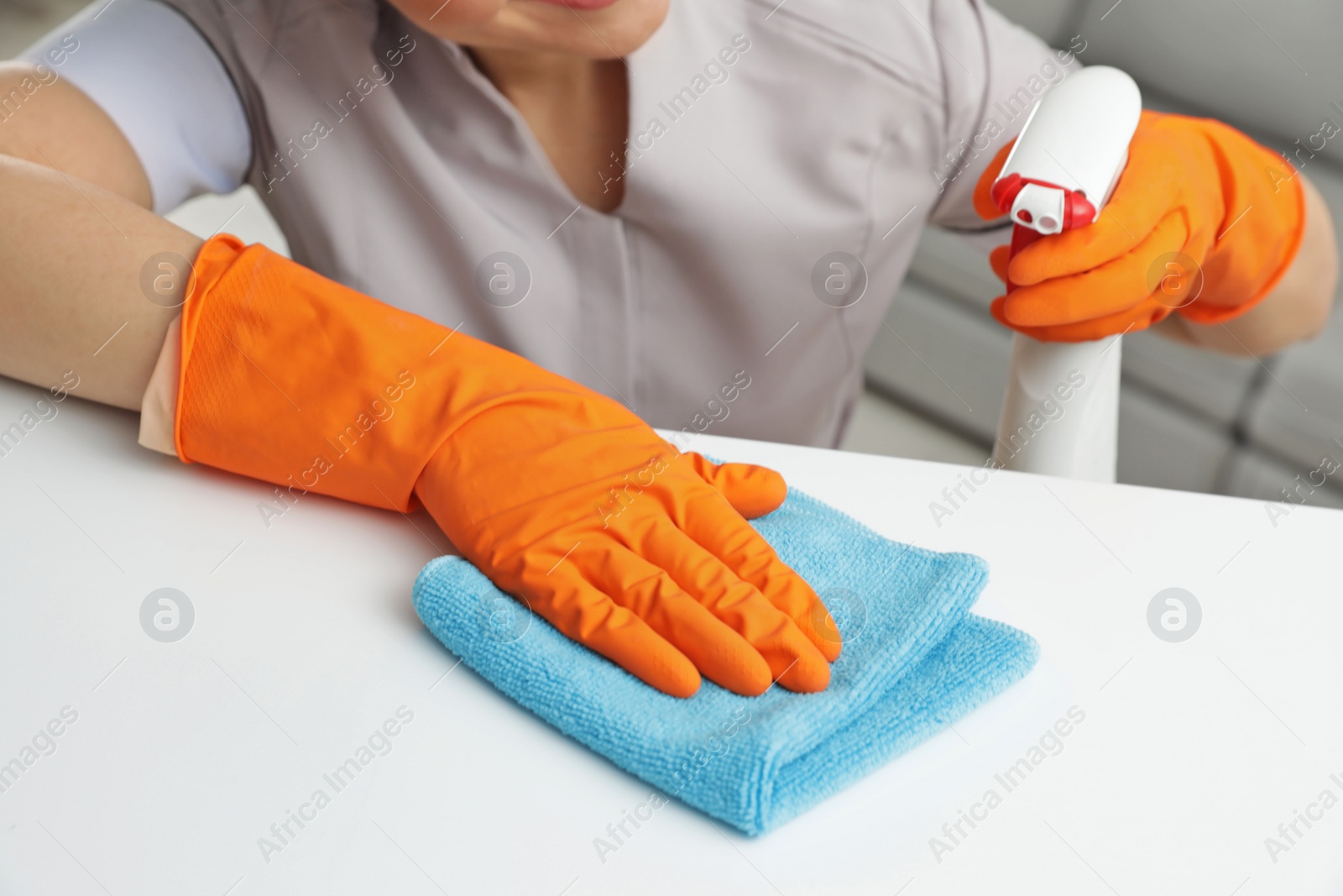 Photo of Young maid cleaning furniture with rag in hotel room, closeup