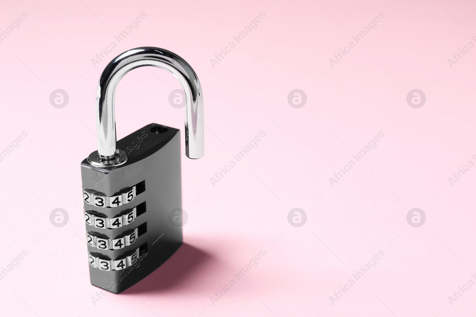 Photo of One steel combination padlock on pink background, closeup. Space for text