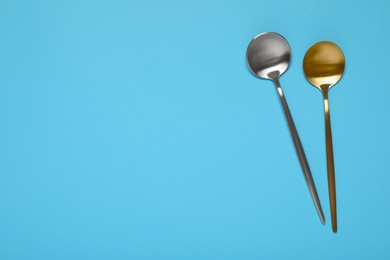 Photo of Shiny spoons on light blue background, top view. Space for text