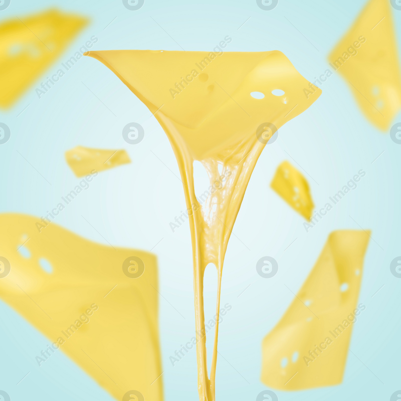 Image of Slices of cheese falling on light blue background