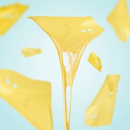 Image of Slices of cheese falling on light blue background