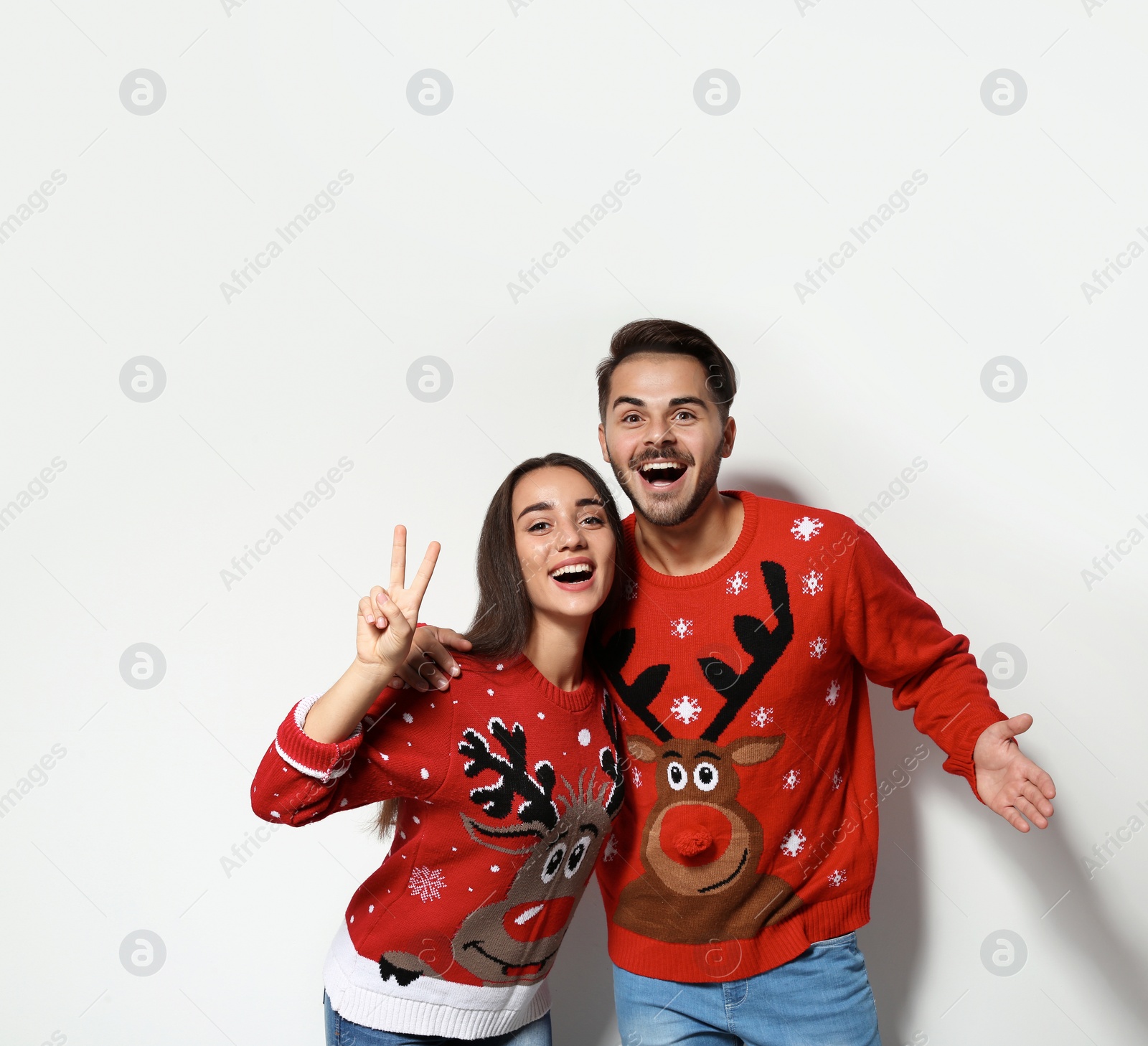 Photo of Young couple in Christmas sweaters on white background