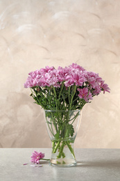 Photo of Beautiful chrysanthemum flowers in glass vase on table