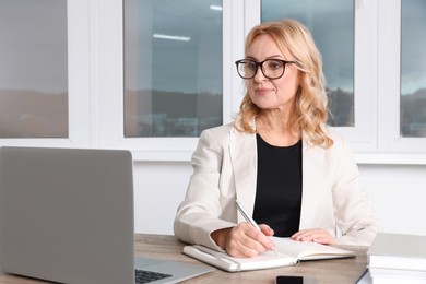 Lady boss working near laptop at desk in office. Successful businesswoman