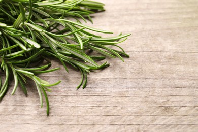 Photo of Sprigs of fresh rosemary on wooden table, closeup. Space for text