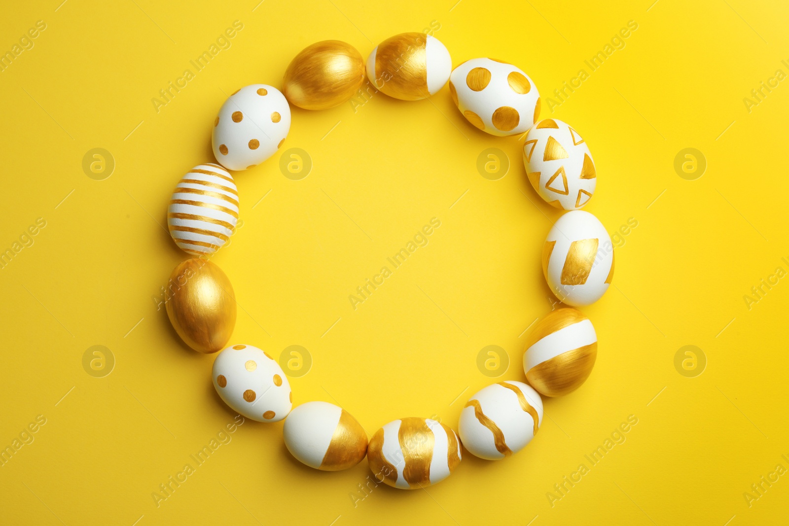 Photo of Frame made of traditional Easter eggs decorated with golden paint on color background, top view. Space for text