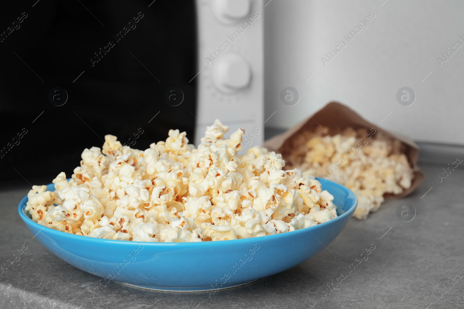 Photo of Bowl with tasty popcorn on table in kitchen