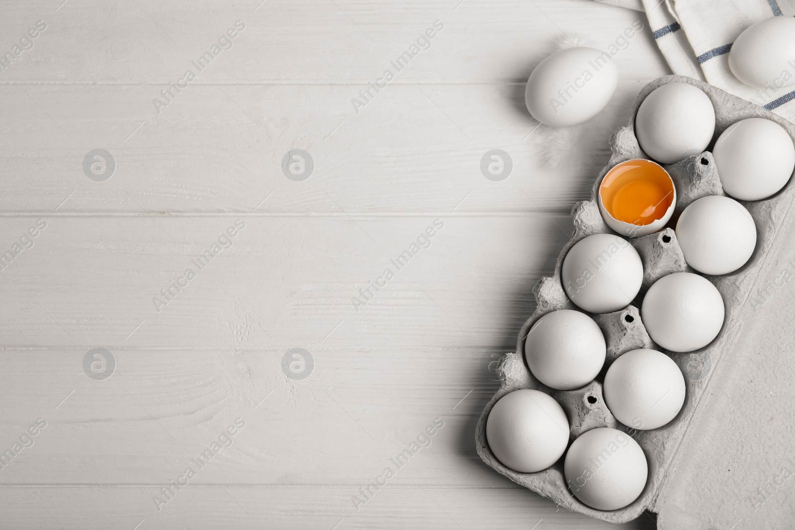 Photo of Fresh raw chicken eggs in box on white wooden table, flat lay. Space for text