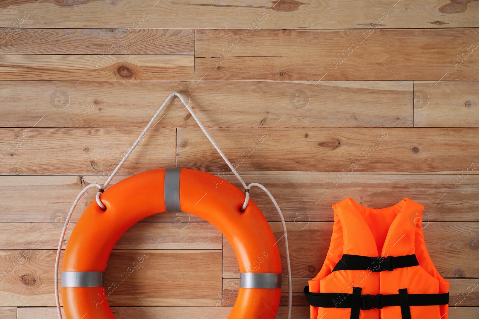 Photo of Orange life jacket and lifebuoy on  wooden background. Rescue equipment