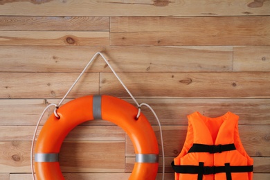 Photo of Orange life jacket and lifebuoy on  wooden background. Rescue equipment