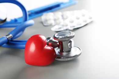 Photo of Stethoscope and small red heart on table. Heart attack concept