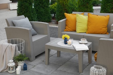 Beautiful rattan garden furniture, soft pillows and different decor elements in backyard