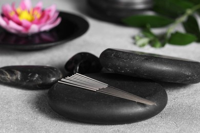 Photo of Stones with acupuncture needles on grey table