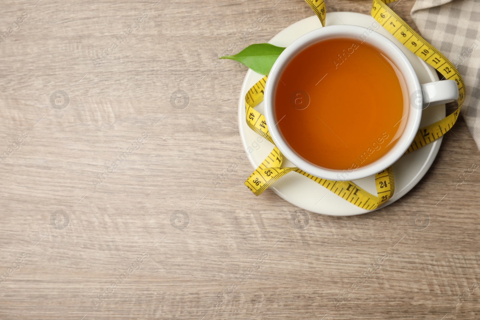 Photo of Flat lay composition with herbal diet tea and measuring tape on wooden table, space for text. Weight loss concept