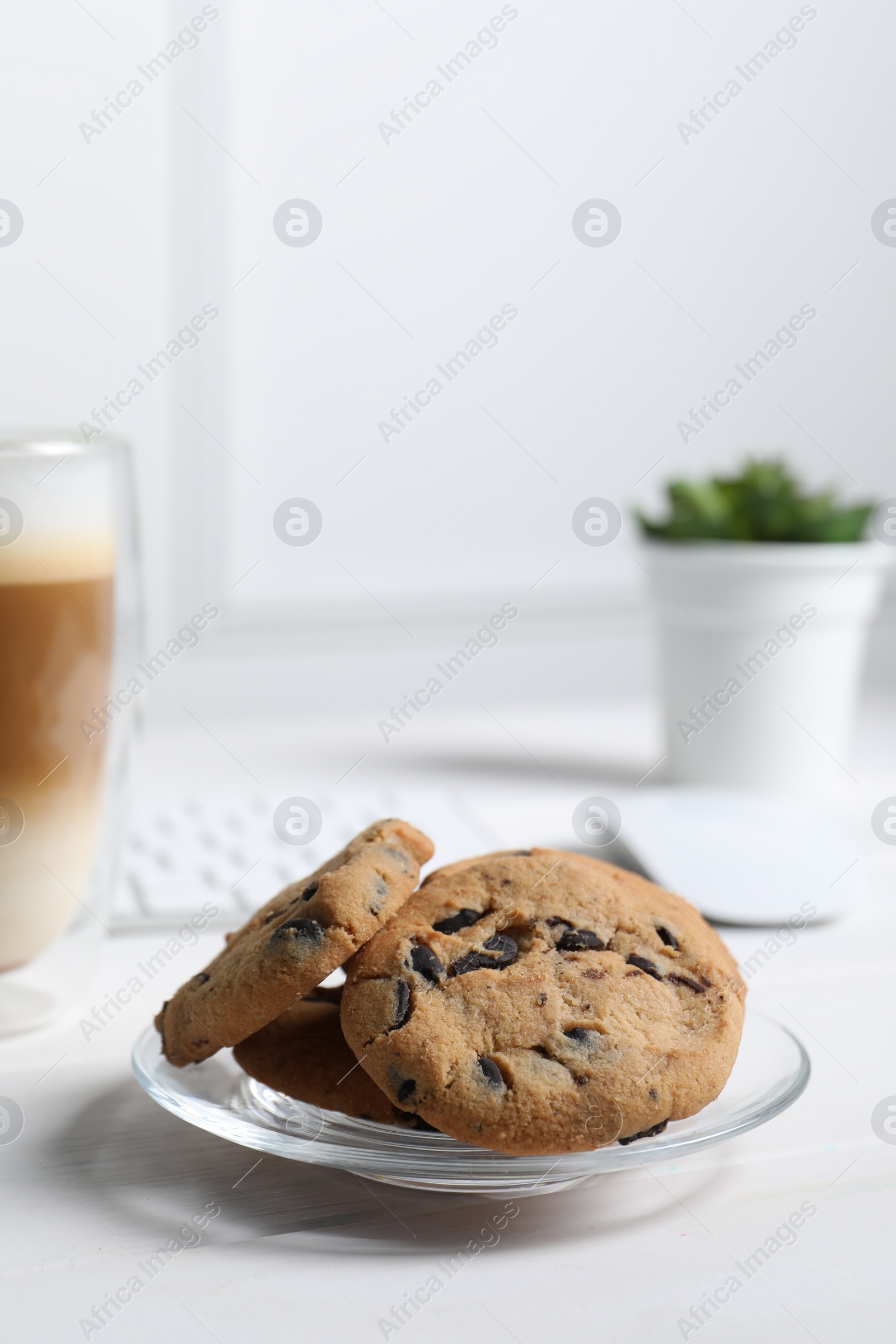 Photo of Chocolate chip cookies on white wooden table in office