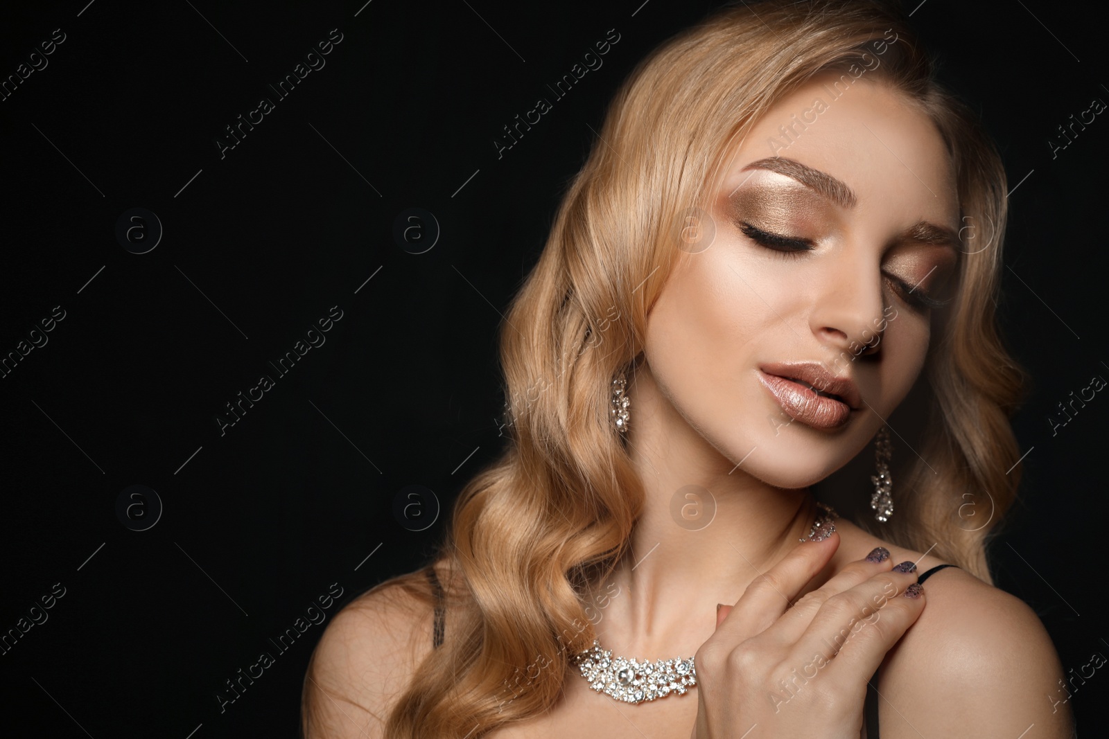 Photo of Beautiful young woman with elegant jewelry on dark background. Space for text