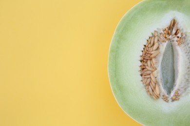 Half of fresh ripe honeydew melon on yellow background, top view. Space for text