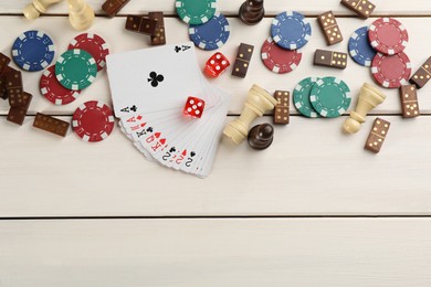 Elements of different board games on white wooden table, flat lay. Space for text