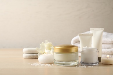 Photo of Spa composition with skin care products and candles on wooden table. Space for text