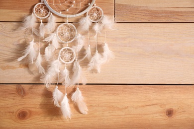 Photo of Beautiful dream catcher hanging on wooden wall, space for text