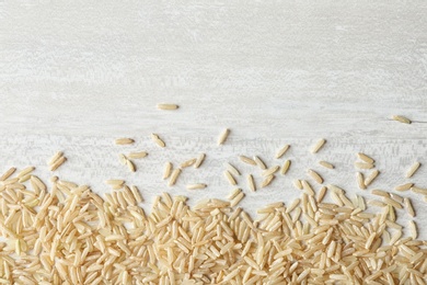 Photo of Brown rice on wooden background, top view with space for text