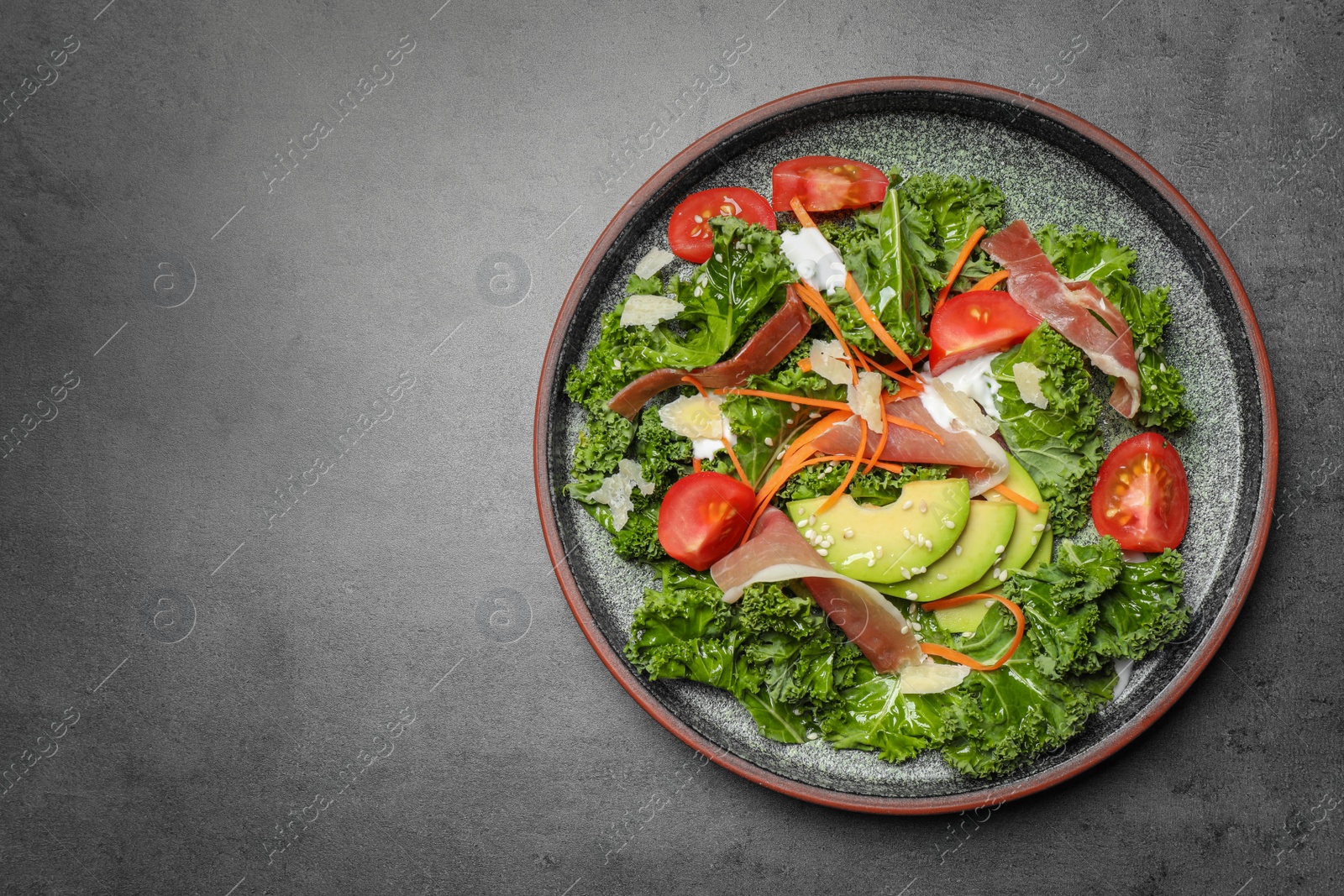 Photo of Delicious kale salad with prosciutto served on grey table, top view. Space for text