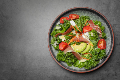 Delicious kale salad with prosciutto served on grey table, top view. Space for text