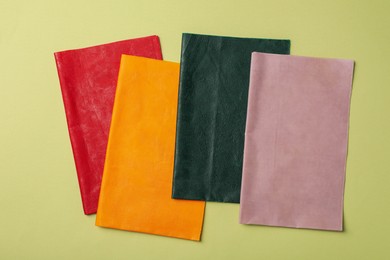 Photo of Different beeswax food wraps on light green background, flat lay