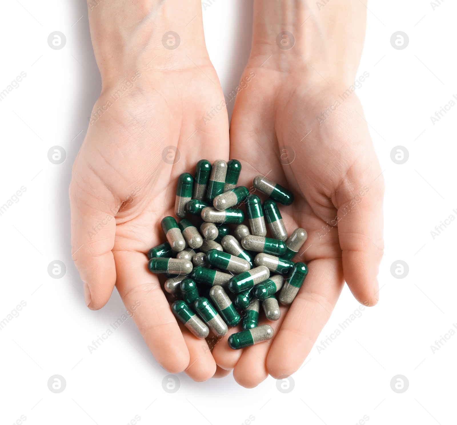 Photo of Woman holding heap of green spirulina capsules on white background, top view