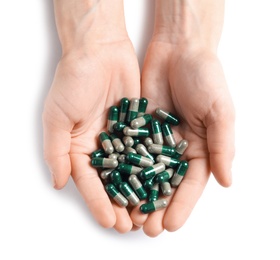 Photo of Woman holding heap of green spirulina capsules on white background, top view