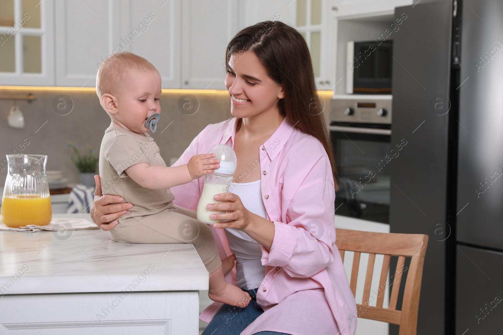 Photo of Happy young woman and her cute little baby spending time together in kitchen